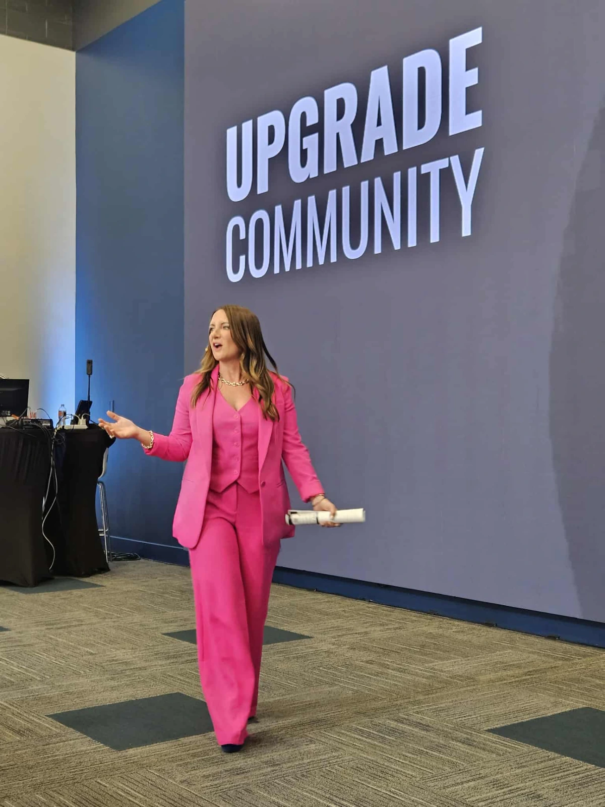 Tara Allen speaking on stage at an Upgrade Community event
